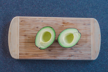 healthy ingredients, avocado cut in halves on cutting board
