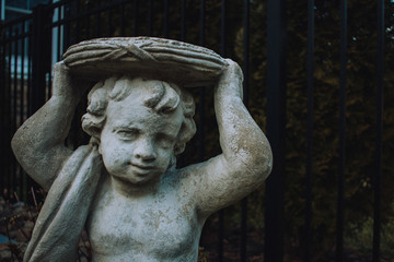 Obraz premium A Statue of a Cherub Holding an Empty Plate