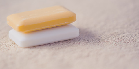 Two bars of soap on a brown towel. Side view.