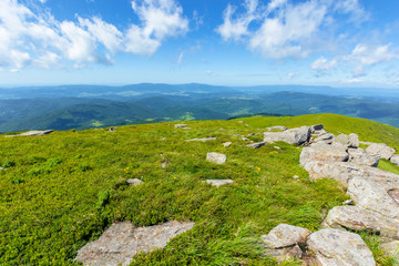 Fototapeta na wymiar rocks on the alpine meadow. wonderful summer landscape of runa mountain. rural valley in the distance. sunny weather with fluffy clouds on the blue sky