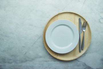 Top view, Closed up empty blank dishware on wooden tray and place on grey granite table. Including fork, knife and spoon.
