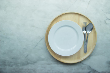 Top view, Closed up empty blank dishware on wooden tray and place on grey granite table. Including fork, knife and spoon.