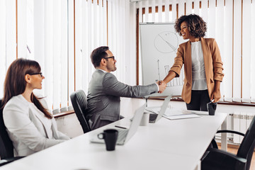 Cheerful businesswoman handshake with a colleague at the meeting