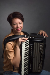 A brunette in a gold shirt, with short haircut, on a light gray background of the Studio. With accordion musician