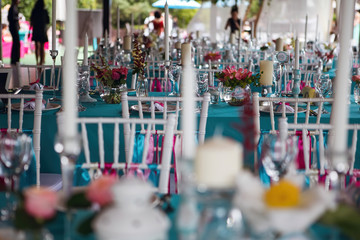 Banquet of the wedding party dinner. Luxury decor decorated tables with flowers, tableware and in turquoise pink colors. Wooden chairs with silk ribbons.