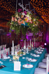 Banquet of the wedding party dinner. Luxury decor decorated tables with flowers, tableware and in turquoise pink colors. Silk ribbons. Romantic inscription: And they lived happily ever after.