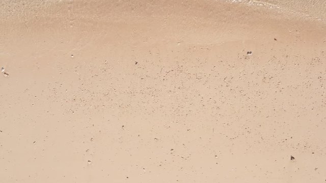 Slow pan along a shell covered sandy beach as waves gentle lap the shore, Okinawa Japan