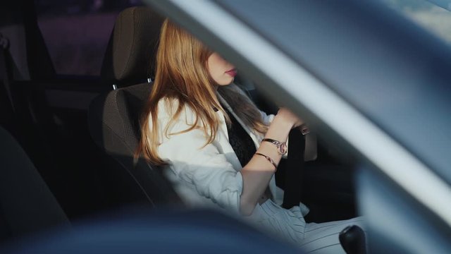 Busy lady fastening seat belt in a comfortable car out of a city