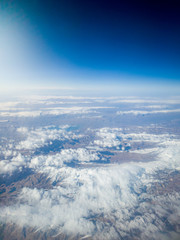 Beautiful photo from the airplane on muntain covered with snow and clouds
