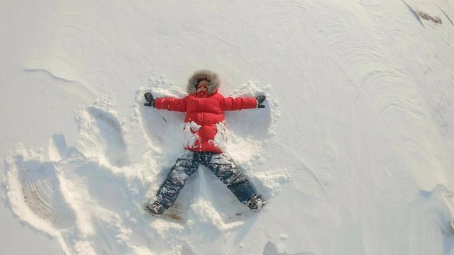A little boy makes a snow angel. Winter recreations concept. Slowmotion shot