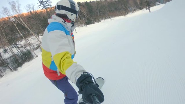 A man rides on a snowboard down the ski slope. Winter recreations concept. Slowmotion shot