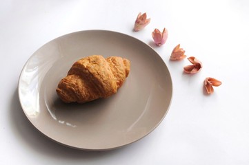 Croissant on the plate with decorated flowers above view