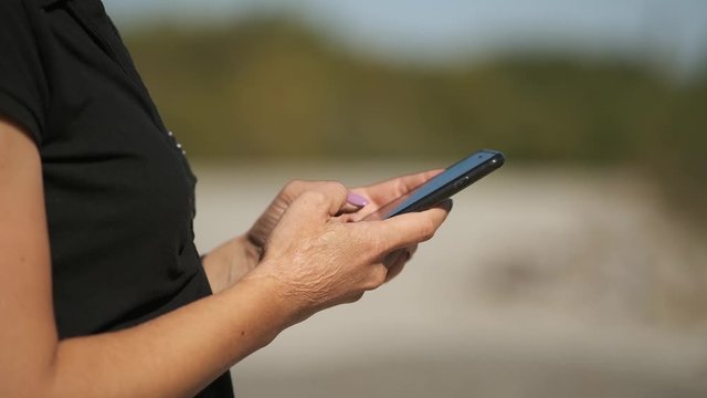 Girl with hands with problem skin touches smartphone, close-up