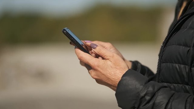 Girl with hands with problem skin touches smartphone, close-up