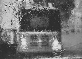 Black and white image of water rain droplets on window of tuk-tuk in Sri Lanka during heavy rain