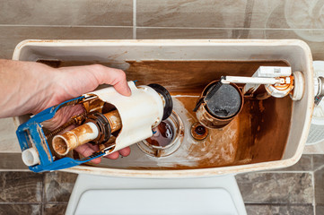 Unscrewing the fittings for draining the water in the toilet flush tank by hand yourself.