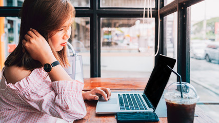 Young woman working on laptop computer  on the wooden desk at Coffee shop, vintage tone.Bussiness concept background,