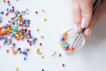 Woman puts out a mosaic of glass with tweezers, fusing, crafting