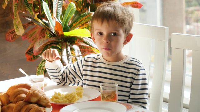 4k video of little 4 years old having lunch in dining room and eating mashed potate with fork