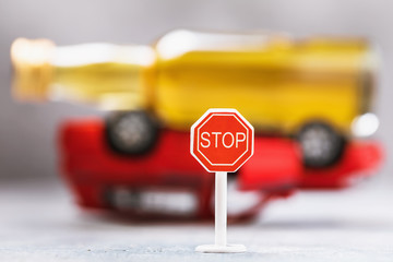 Road sign and a bottle of whiskey on an inverted car. Concept on the topic of drunk driving