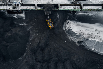 Open pit mine, extractive industry excavator loads black coal into freight wagon of train, top view...
