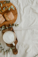 Breakfast on the bed with coffee and rolls, top view
