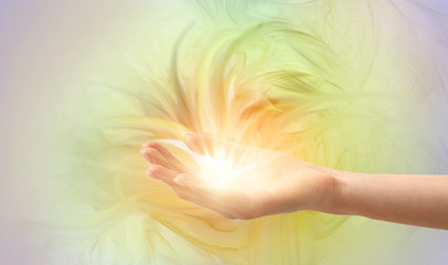 Female hand with shining energy on color background