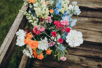 bouquet of wildflowers stands on wooden steps in the forest against a background of green grass