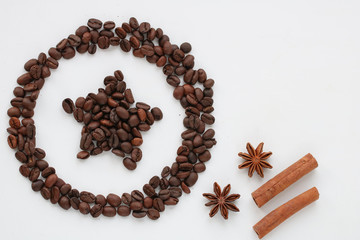 Star shape and circle around made of coffee beans on white background with cinnamon sticks, star anise with copy space