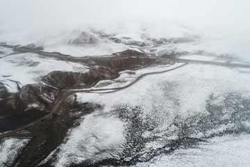 Country road winding through a valley surrounded by snowy mountains