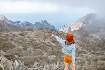 Young stylish woman enjoying beautiful landscapes, traveling highly in the mountains on Tenerife island, Spain