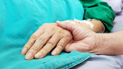 Oncologist doctor holding patient's hand in hospital. Showing all love, empathy, helping and encouragement. He has end stage cancer disease. Healthcare in end of life and palliative care concept - obrazy, fototapety, plakaty