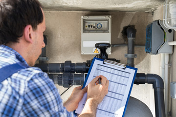 Worker Inspecting Water Pump And Pipes