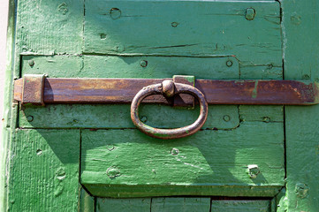 Closeup of an old green wooden door with a rusty iron latch. Veneto, Italy, Europe
