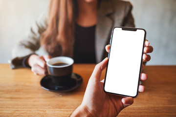 Mockup image of a woman holding and showing white mobile phone with blank desktop screen to someone
