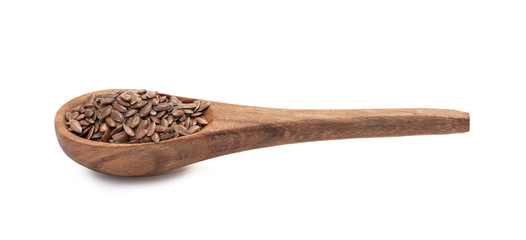 Linseeds or flax seed on a brown wooden spoon seen obliquely from the side and above and isolated on white background