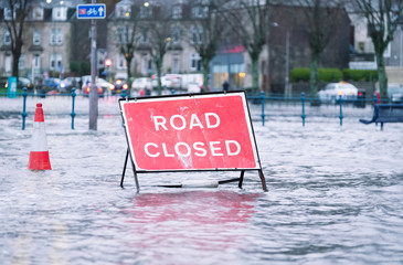Road flood closed sign under deep water during bad extreme heavy rain storm weather in UK