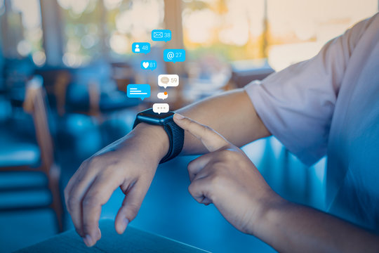 Person using a social media marketing concept on smartwatch with notification icons of like, message, comment and star above smartwatch screen.