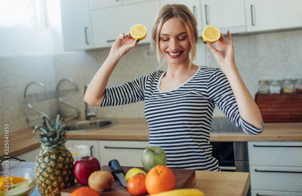 Wall mural Young smiling woman with lemons