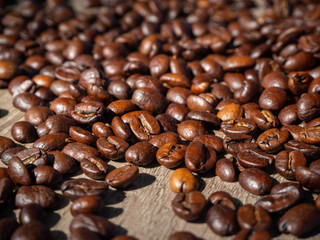 Black coffee in grains on the surface of a wooden table.