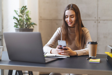 Female texting on smartphone during lunch break at workplace. Manager in office calling customers in front of laptop. Female using mobile phone for entertainment and social communication in media.