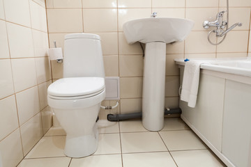 Fototapeta na wymiar Interior of simple half bathroom with toilet, sink and bath with shower, white sanitary ware