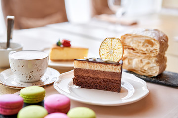 Chocolate sponge cake, with mousse, decorated with Orange slice and meringue. Breakfast in the cafe, morning coffee. on wooden table.