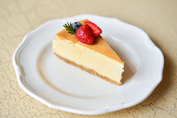 Closeup piece of delicious cheesecake with strawberry and mint leaves on white plate.