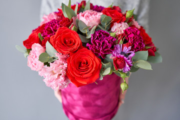 Red and violet floral bunch in Velour round box. European floral shop. Bouquet of beautiful Mixed flowers in woman hand.