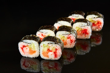 Traditional sushi roll with salmon, cream cheese, shrimp and cucumber on black stone. Japanese food