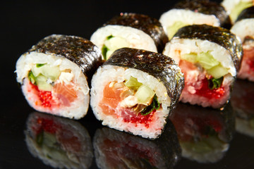 Traditional sushi roll with salmon, cream cheese, caviar and cucumber on black stone. Japanese food