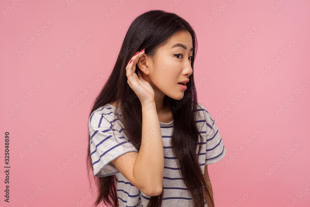 Wall mural what? i can't hear! portrait of curious girl with long brunette hair in striped t-shirt holding palm