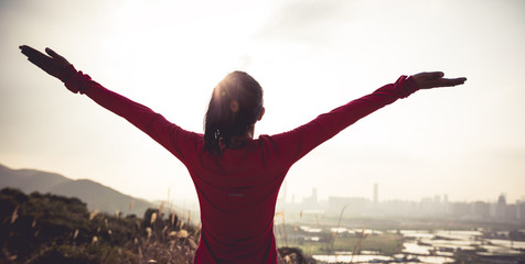 Fototapeta premium Freedom woman open arms on mountains next to modern city