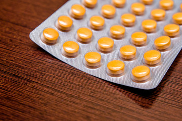 A package of orange tablets is placed on a brown background